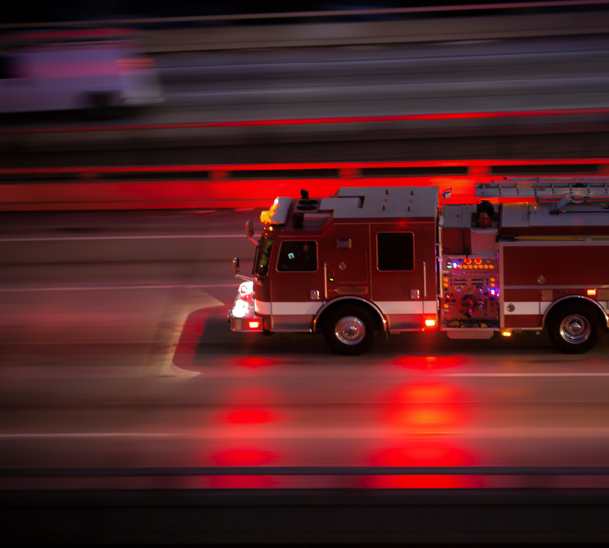 Fire truck driving fast on a street at night
